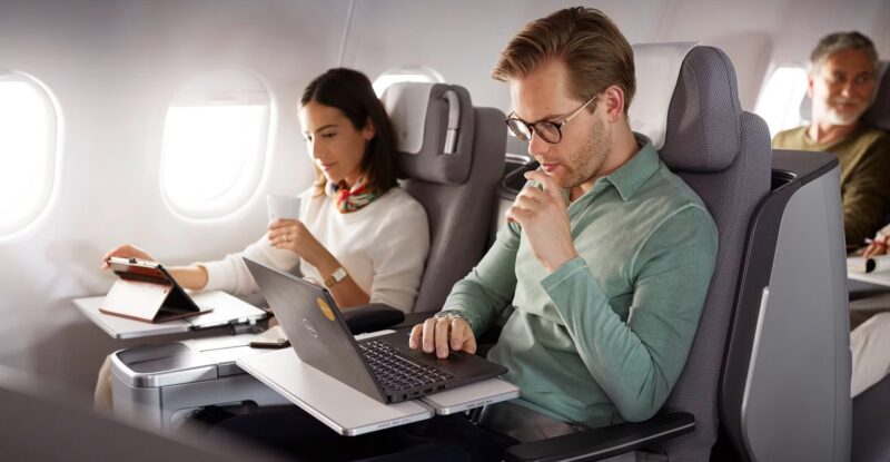 A man and a woman use inflight connectivity on their devices in business class aboard a Discover A330